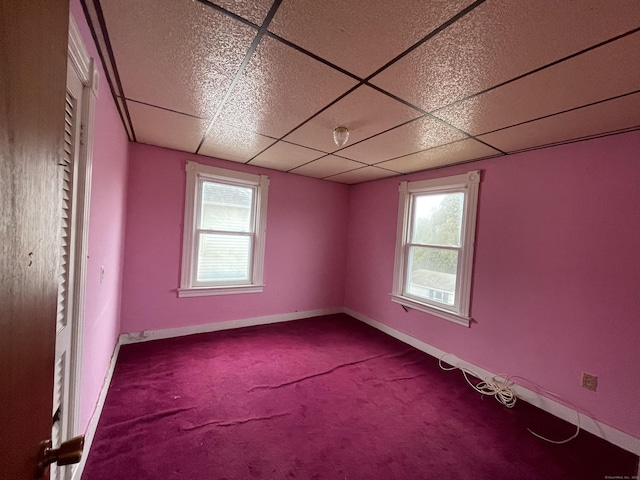 carpeted spare room with a drop ceiling