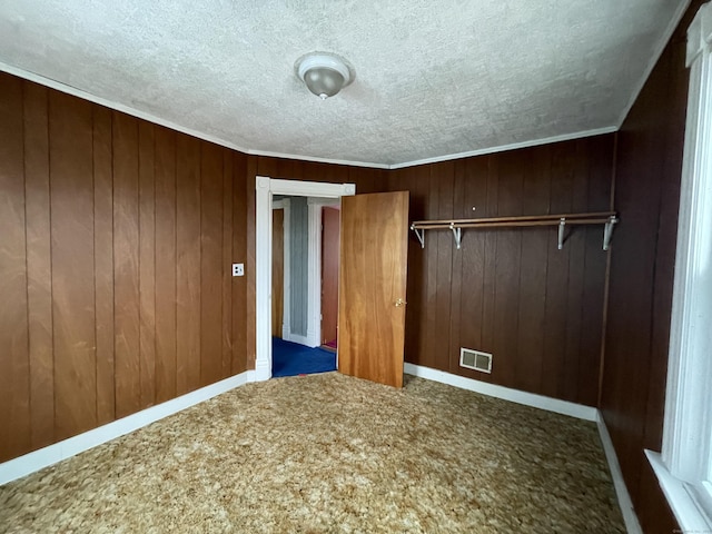 unfurnished bedroom featuring ornamental molding, wooden walls, and a closet