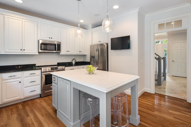 kitchen featuring a breakfast bar, appliances with stainless steel finishes, a center island, and white cabinets