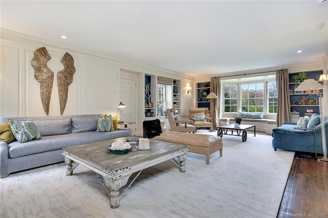 living room featuring hardwood / wood-style floors, built in features, and ornamental molding