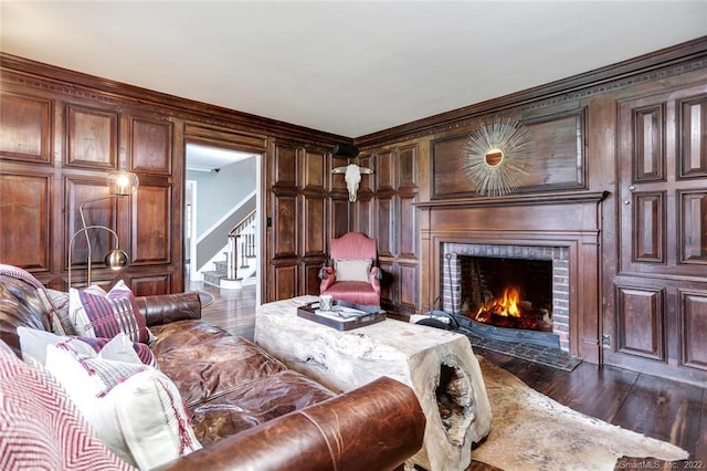 living room with wooden walls, dark hardwood / wood-style floors, and a brick fireplace