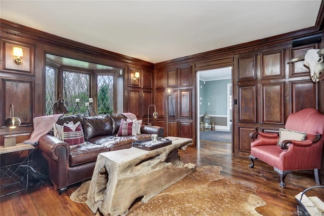 living room with dark wood-type flooring, crown molding, and wooden walls