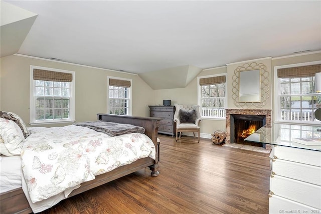 bedroom with hardwood / wood-style flooring, lofted ceiling, a fireplace, and ornamental molding