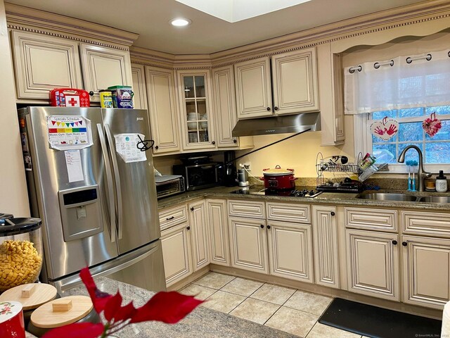 kitchen with sink, light tile patterned floors, stainless steel fridge, black electric stovetop, and cream cabinets