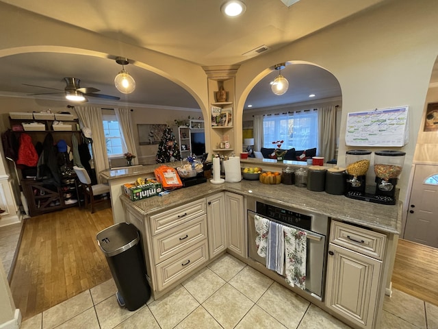 kitchen with light stone counters, light hardwood / wood-style flooring, ornamental molding, and cream cabinetry