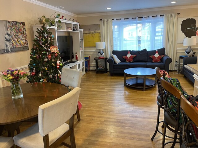 dining area with ornamental molding and light hardwood / wood-style floors