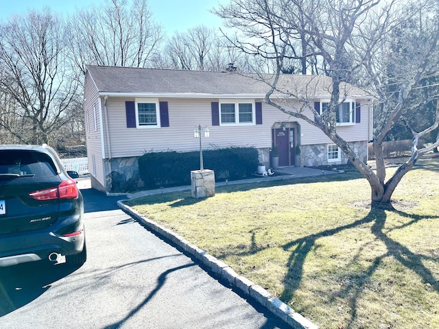 bi-level home featuring a shingled roof and a front yard