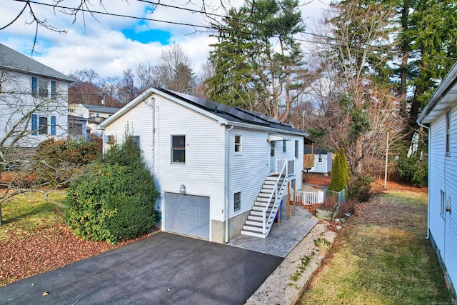 view of property exterior featuring solar panels and a garage