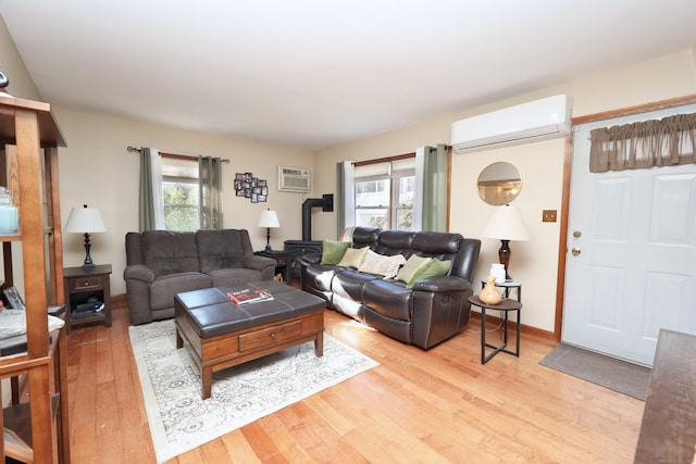 living room featuring a wall unit AC, a wealth of natural light, and light hardwood / wood-style floors