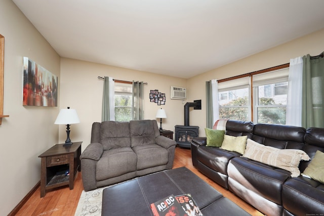 living room with a wood stove, hardwood / wood-style floors, a healthy amount of sunlight, and a wall mounted AC