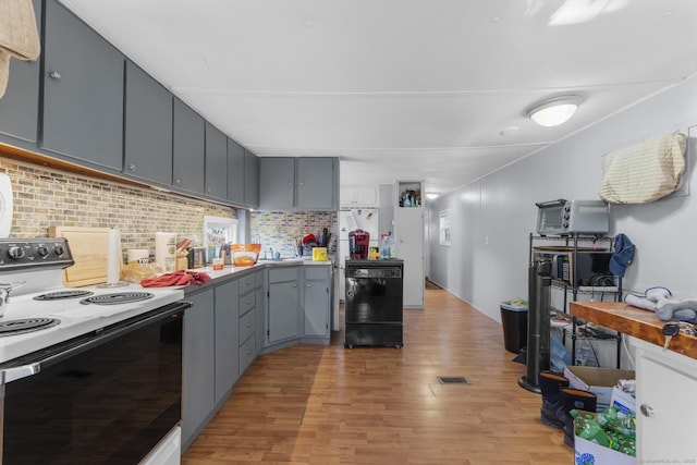 kitchen featuring white range with electric cooktop, decorative backsplash, gray cabinets, black dishwasher, and light hardwood / wood-style floors