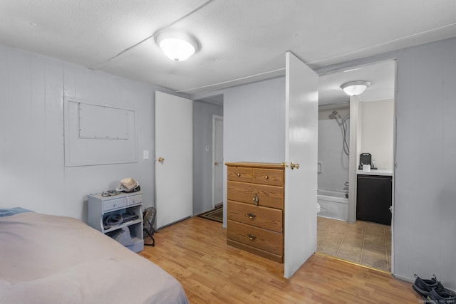 bedroom with hardwood / wood-style flooring, ensuite bathroom, and a textured ceiling