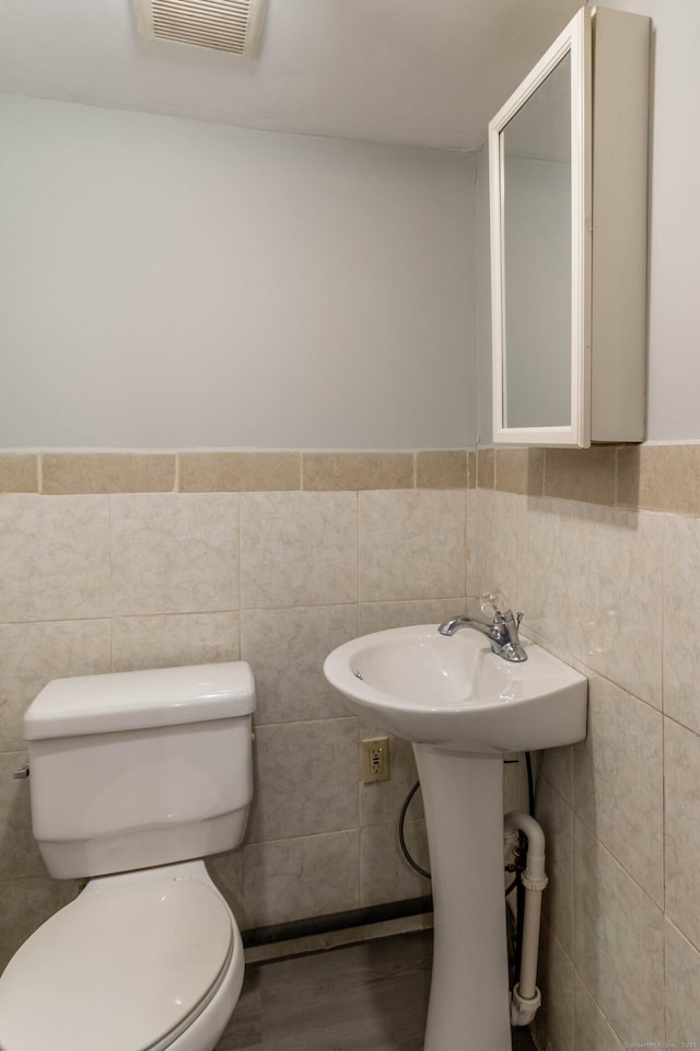 bathroom featuring toilet and tile walls