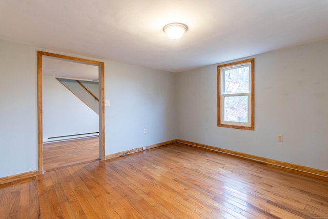 spare room with baseboard heating and light hardwood / wood-style flooring