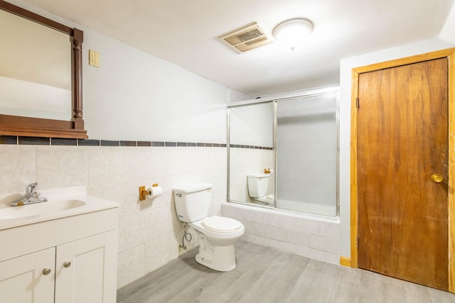 full bathroom featuring vanity, toilet, combined bath / shower with glass door, and wood-type flooring