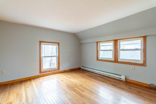 spare room featuring light hardwood / wood-style flooring, vaulted ceiling, and a baseboard heating unit