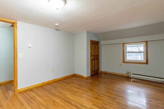 interior space with light hardwood / wood-style flooring, lofted ceiling, and a baseboard heating unit