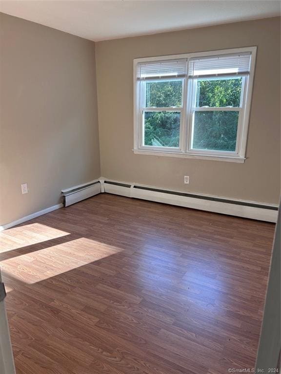 spare room featuring dark wood-type flooring and a baseboard heating unit