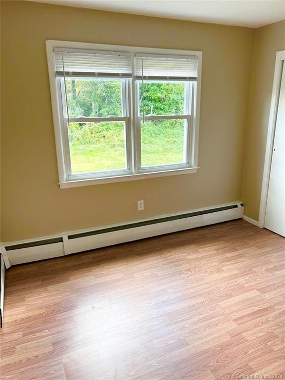 unfurnished room with light hardwood / wood-style floors and a baseboard heating unit