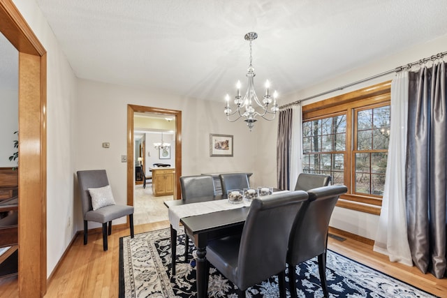 dining room with a chandelier, a textured ceiling, and light hardwood / wood-style floors