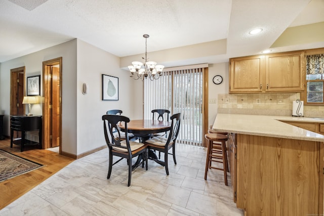 dining space featuring light hardwood / wood-style flooring, a textured ceiling, and an inviting chandelier