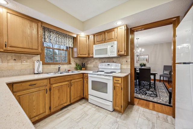 kitchen with backsplash, sink, white appliances, and an inviting chandelier