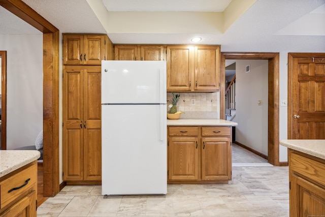 kitchen with tasteful backsplash, light stone countertops, and white refrigerator