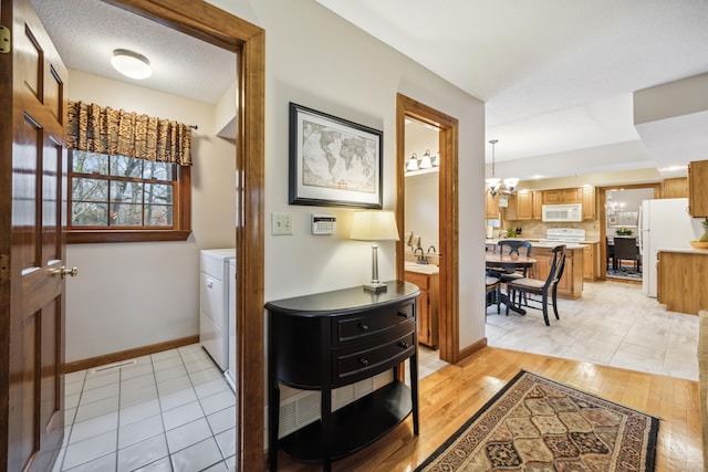 interior space featuring light hardwood / wood-style flooring, a chandelier, a textured ceiling, and washer / dryer