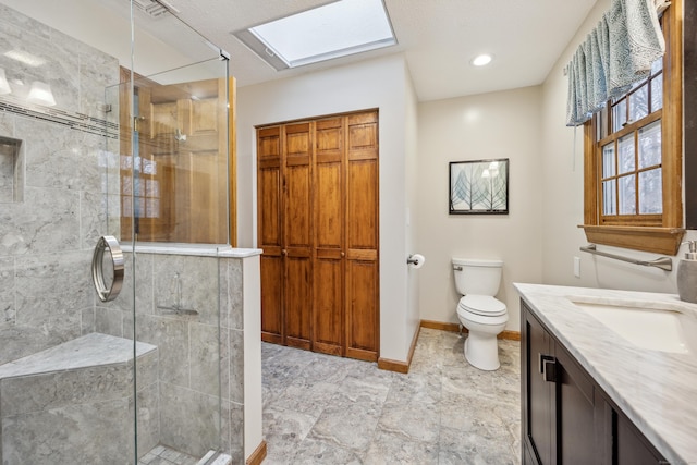 bathroom featuring vanity, a skylight, toilet, and an enclosed shower