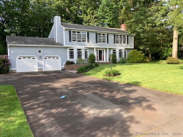 colonial-style house featuring a front yard and a garage