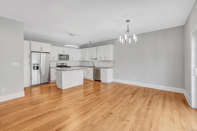 kitchen featuring a kitchen island, pendant lighting, decorative backsplash, white cabinets, and appliances with stainless steel finishes