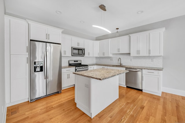 kitchen with white cabinetry, a center island, pendant lighting, and appliances with stainless steel finishes