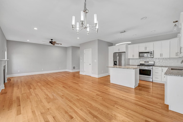 kitchen featuring a center island, ceiling fan with notable chandelier, tasteful backsplash, white cabinetry, and stainless steel appliances