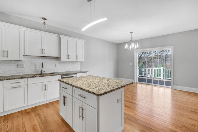 kitchen featuring a center island, sink, white cabinets, and hanging light fixtures