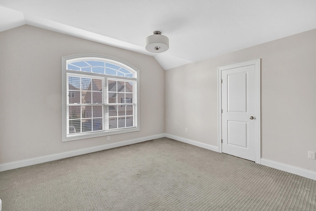 empty room featuring light colored carpet and vaulted ceiling