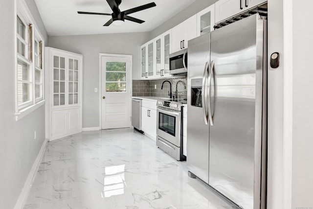 kitchen featuring decorative backsplash, stainless steel appliances, ceiling fan, white cabinetry, and lofted ceiling