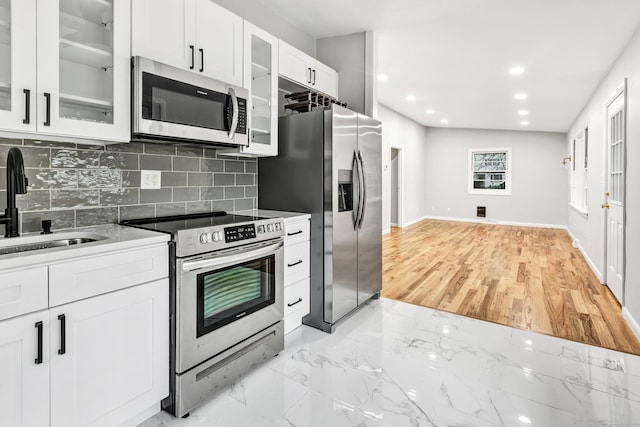 kitchen with white cabinets, sink, stainless steel appliances, and tasteful backsplash