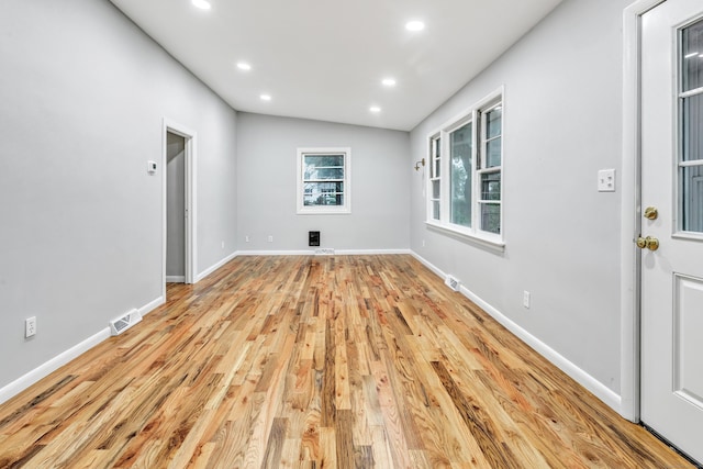 spare room with light hardwood / wood-style floors and vaulted ceiling