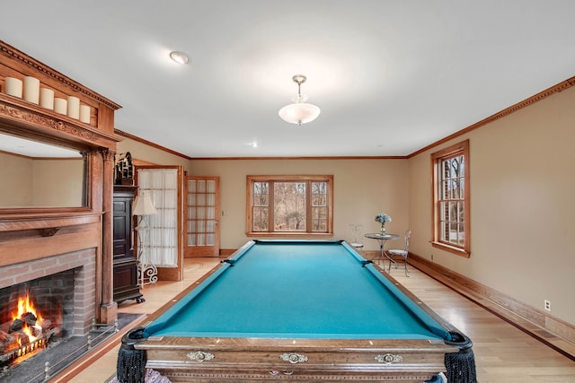 recreation room with a fireplace, wood-type flooring, ornamental molding, and billiards