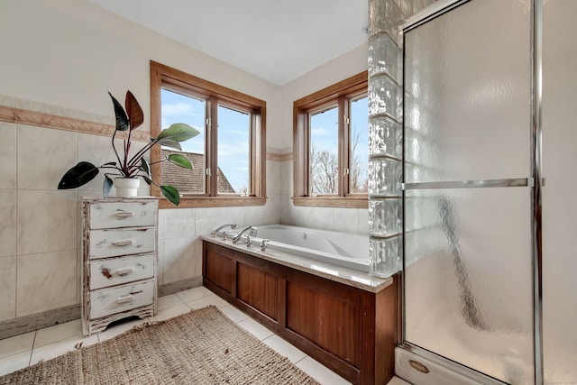 full bathroom with a wainscoted wall, tile walls, tile patterned flooring, a shower stall, and a garden tub