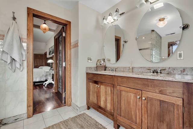 ensuite bathroom with connected bathroom, tile patterned flooring, a sink, and double vanity
