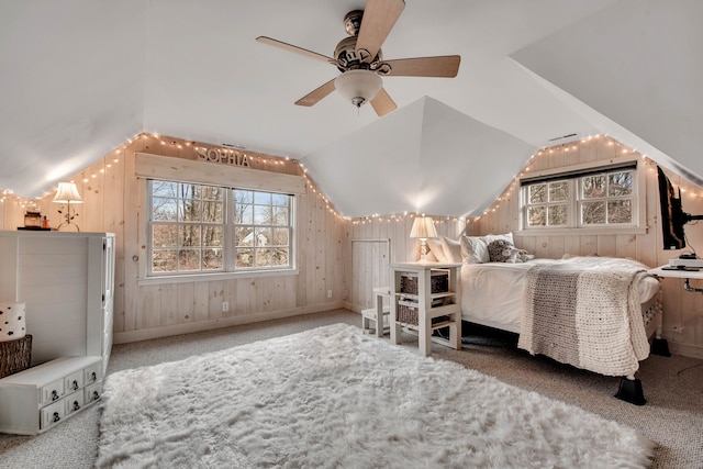 carpeted bedroom featuring ceiling fan, wood walls, and vaulted ceiling