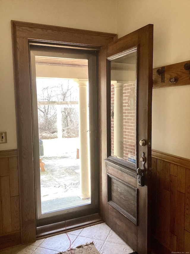 entryway featuring wainscoting, wood walls, and light tile patterned floors