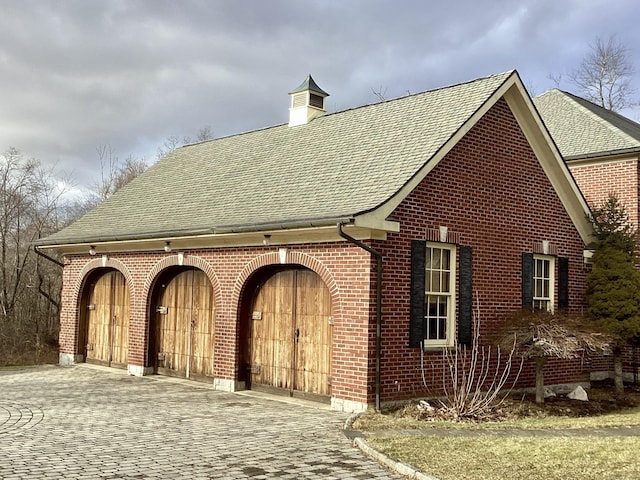 exterior space with a shingled roof and brick siding