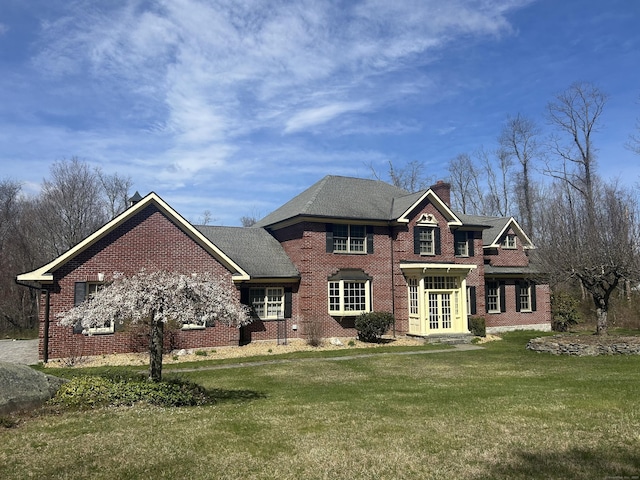 view of front of property with brick siding, french doors, a chimney, and a front lawn