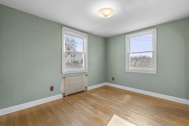 empty room featuring radiator heating unit and light hardwood / wood-style flooring