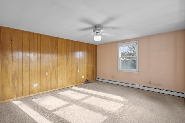 spare room with ceiling fan, light carpet, wooden walls, and a baseboard radiator