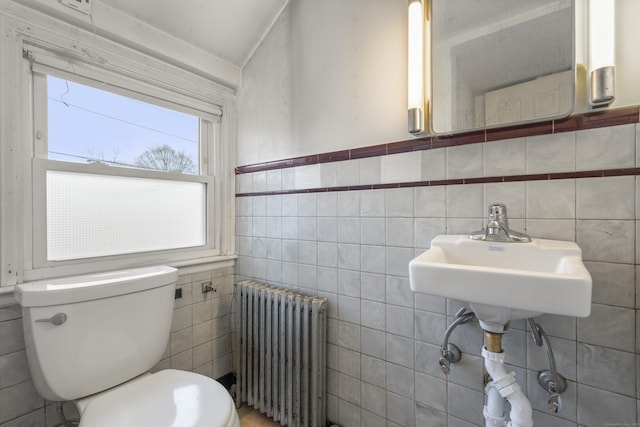 bathroom with sink, toilet, radiator heating unit, and tile walls