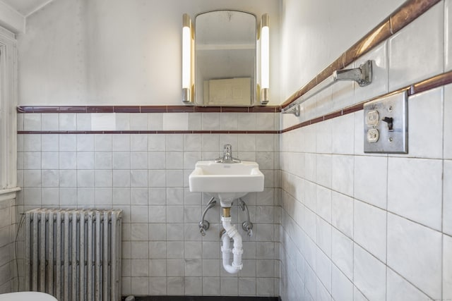 bathroom with sink, radiator heating unit, and tile walls