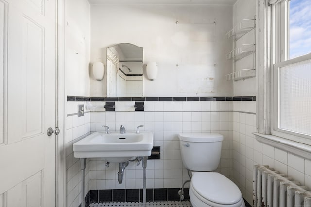 bathroom with radiator heating unit, tile walls, and toilet